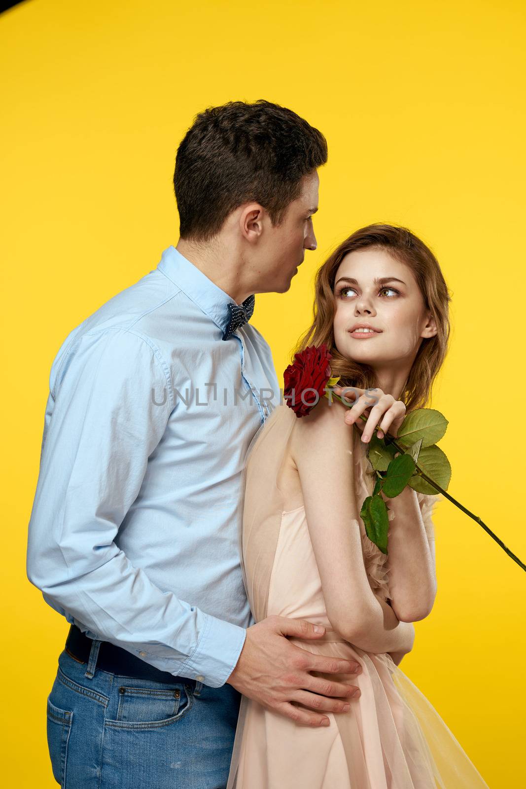 Enamored man and woman with red rose on yellow background cropped view close-up romance. High quality photo