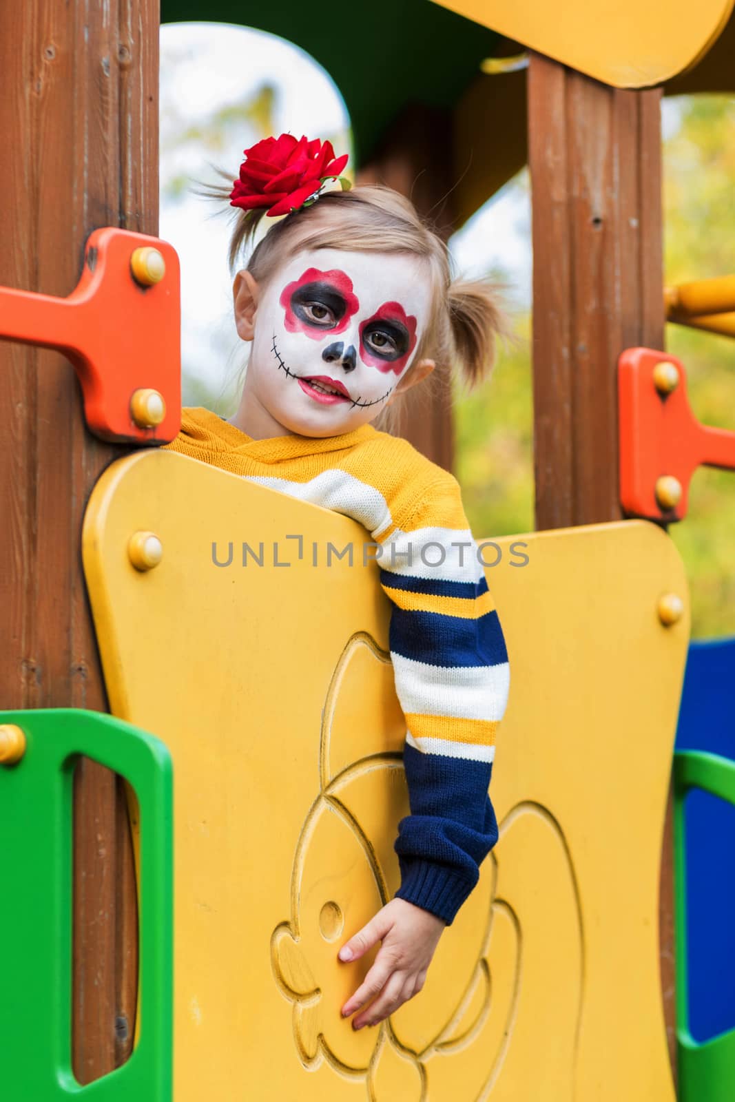 A little girl with Painted Face, climbed the slide on the playground by galinasharapova