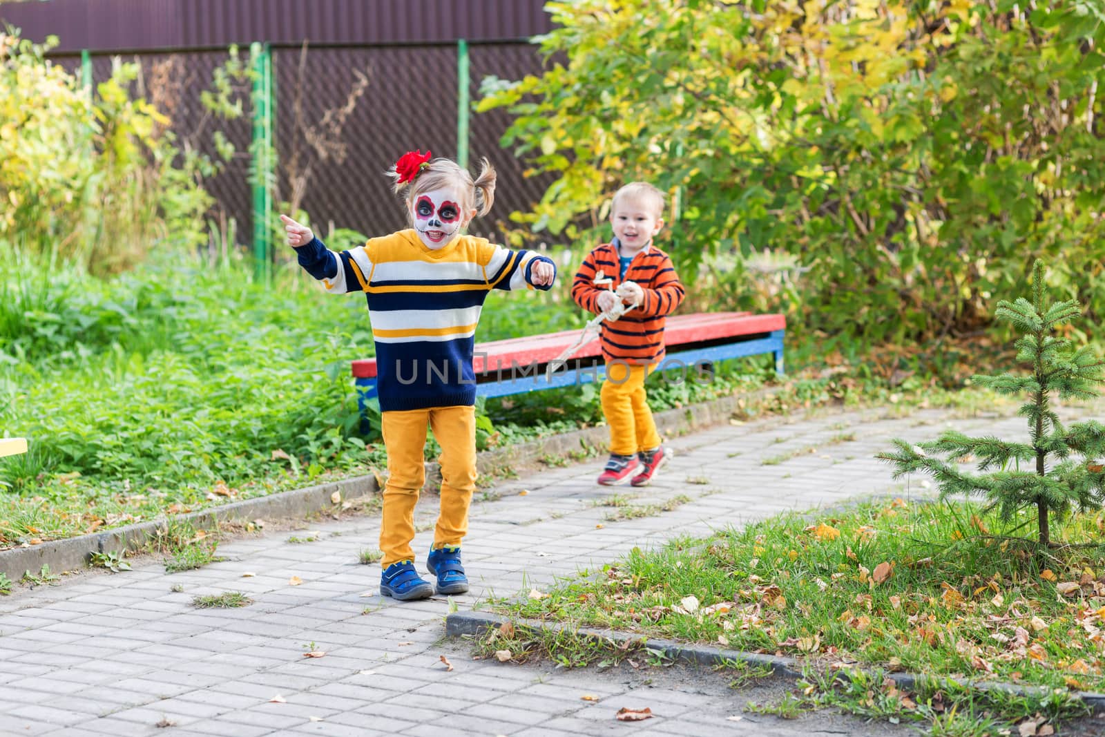 A little girl with Painted Face, running away from brother in the playground by galinasharapova