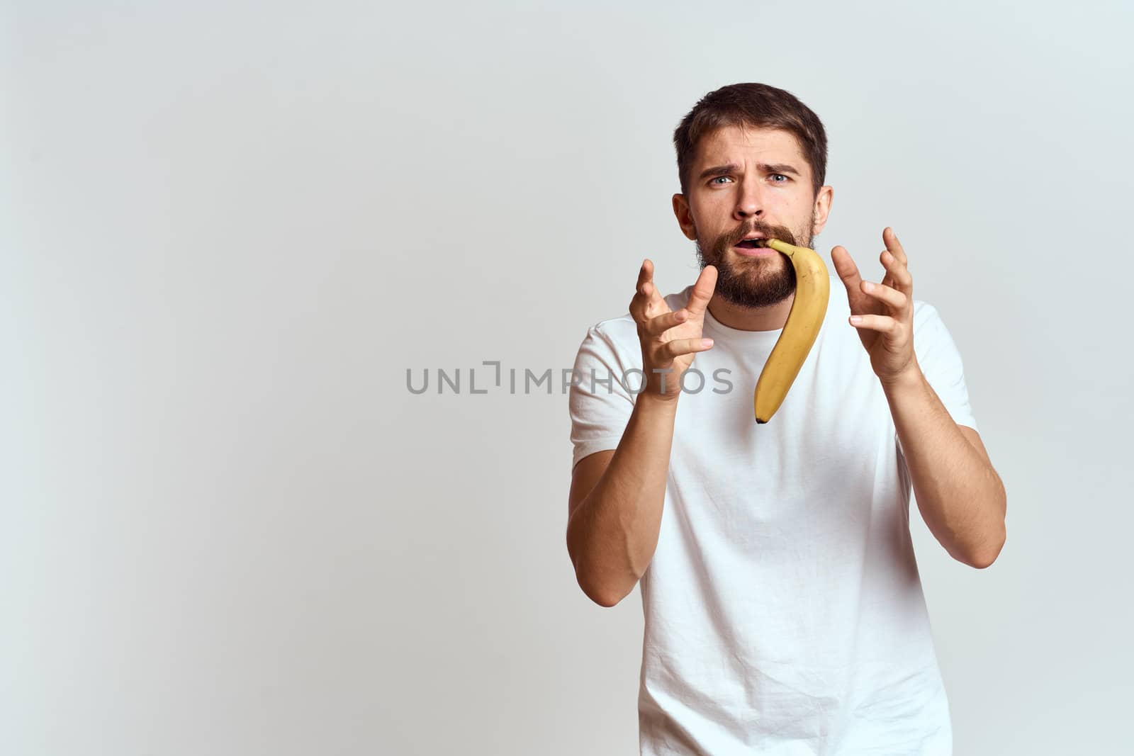 Cheerful man with a banana in his hands on a light background fun emotions Cropped view Copy Space. High quality photo