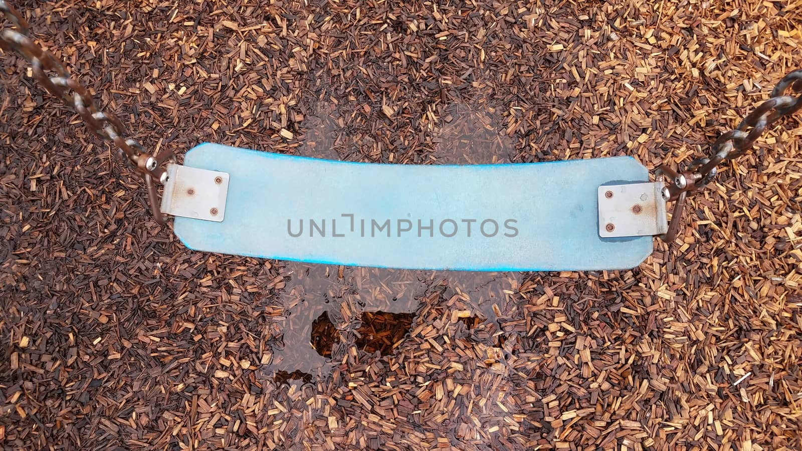 blue swing seat with water puddle on mulch or wood chips
