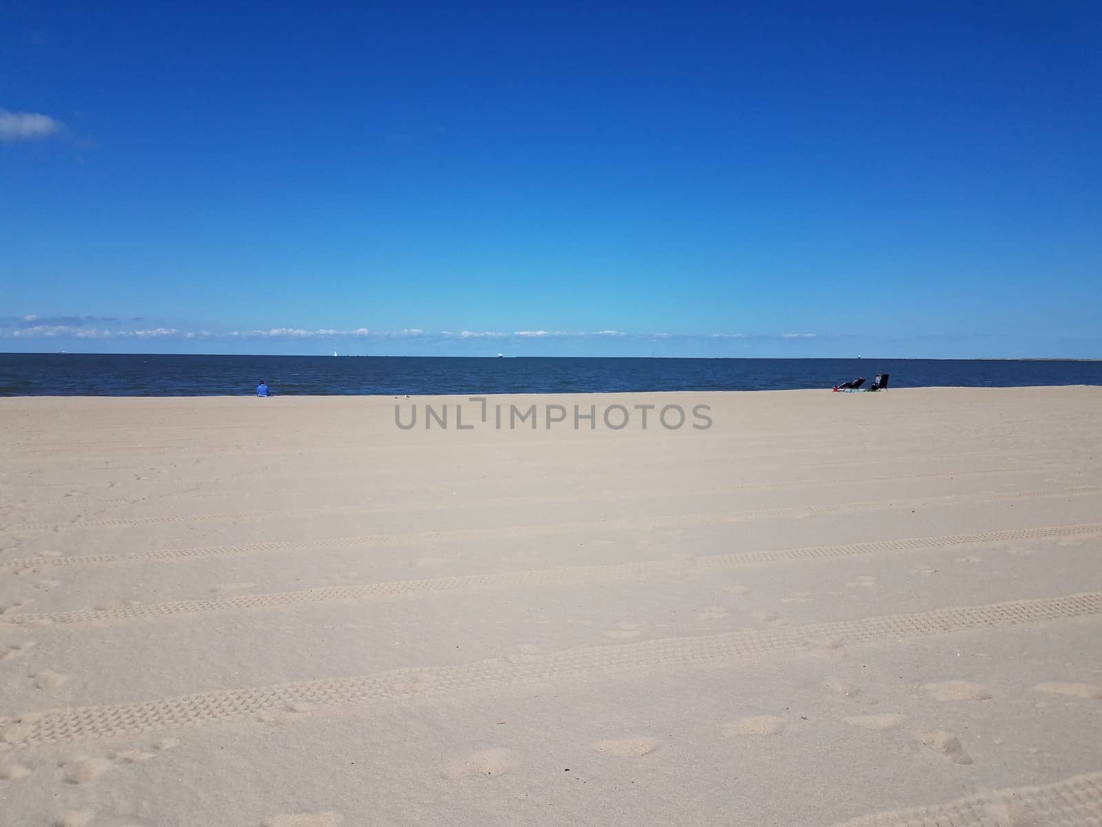 tire tracks and foot prints on sand on combed beach and sea water