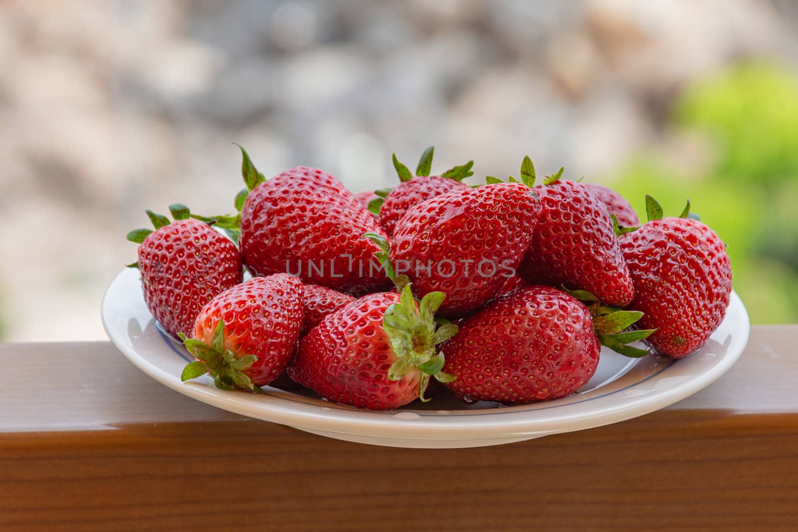 Red ripe strawberries on a plate. Blurry background, close-up. Stock photo