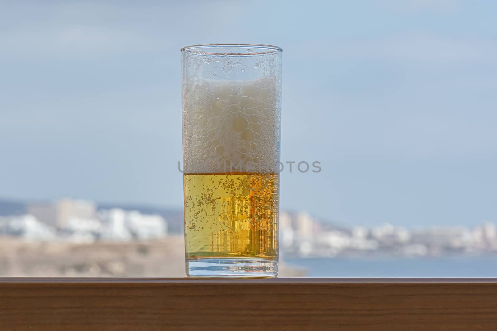 glass of light foamy beer in close-up on a blurry background. Stock photo
