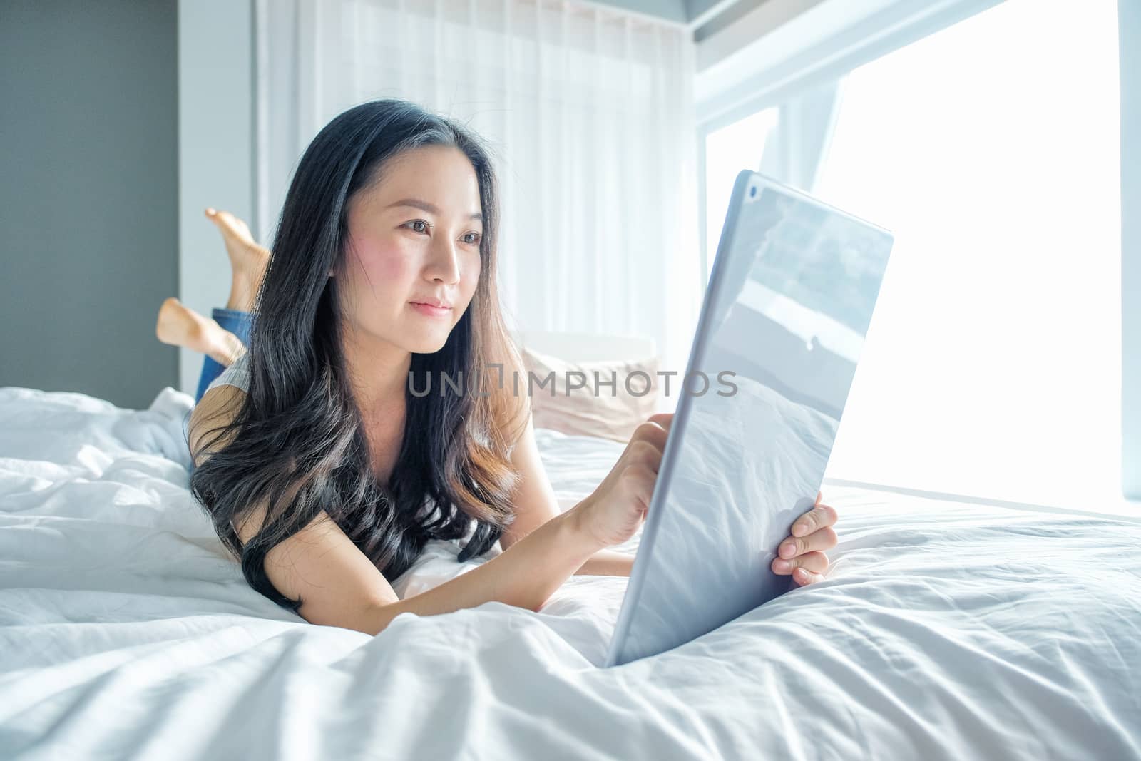 Yound woman using tablet on the bed 