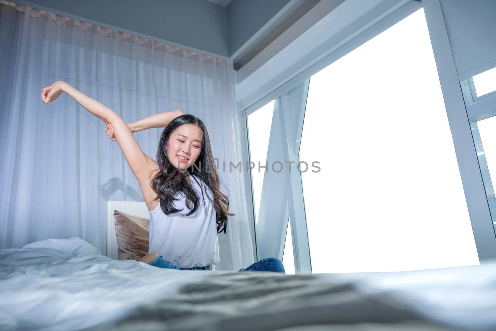 Woman stretch herself out after waking up in the morning on whit by Surasak