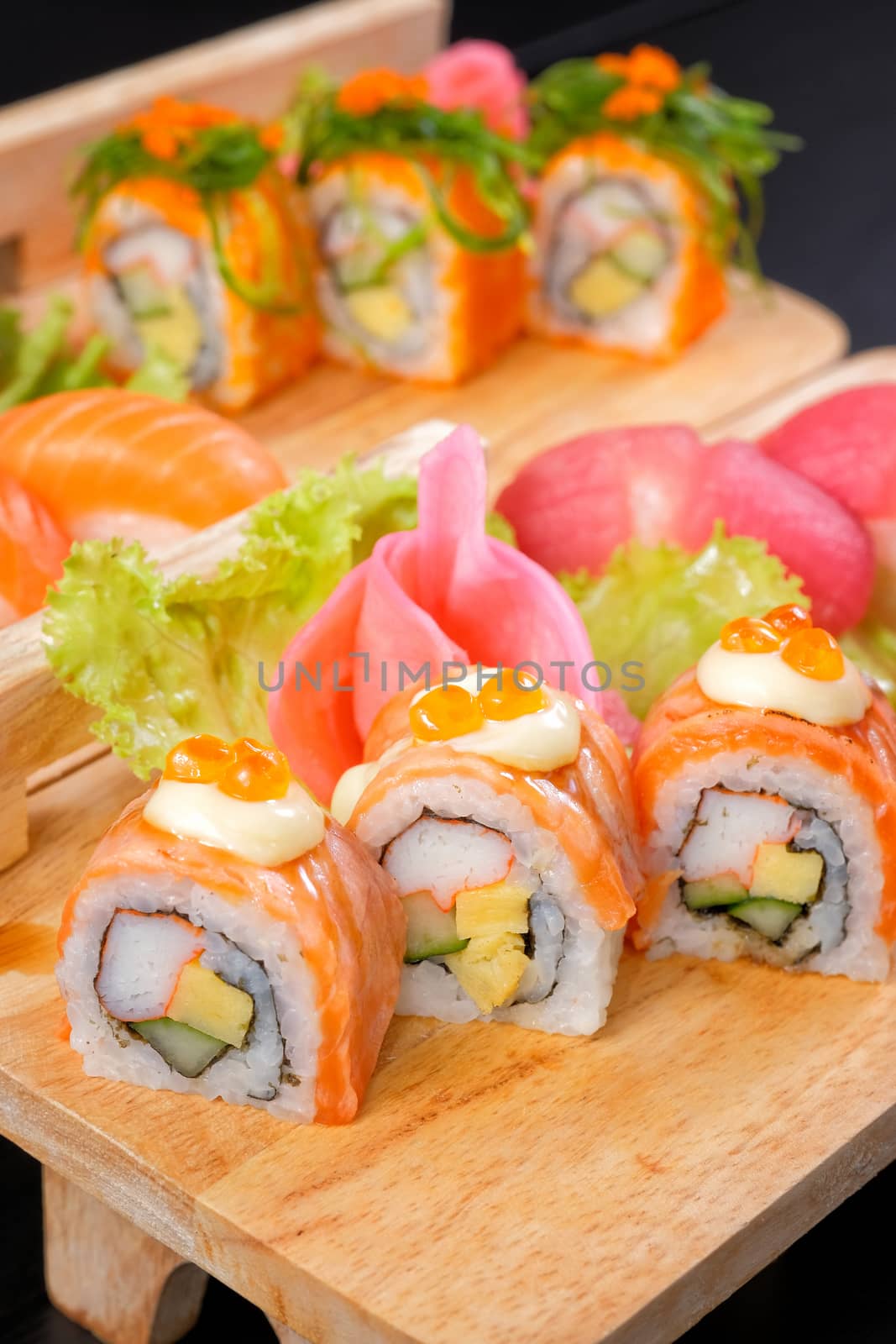 Japanese Cuisine - Sushi Roll on wood plate in black background by Surasak