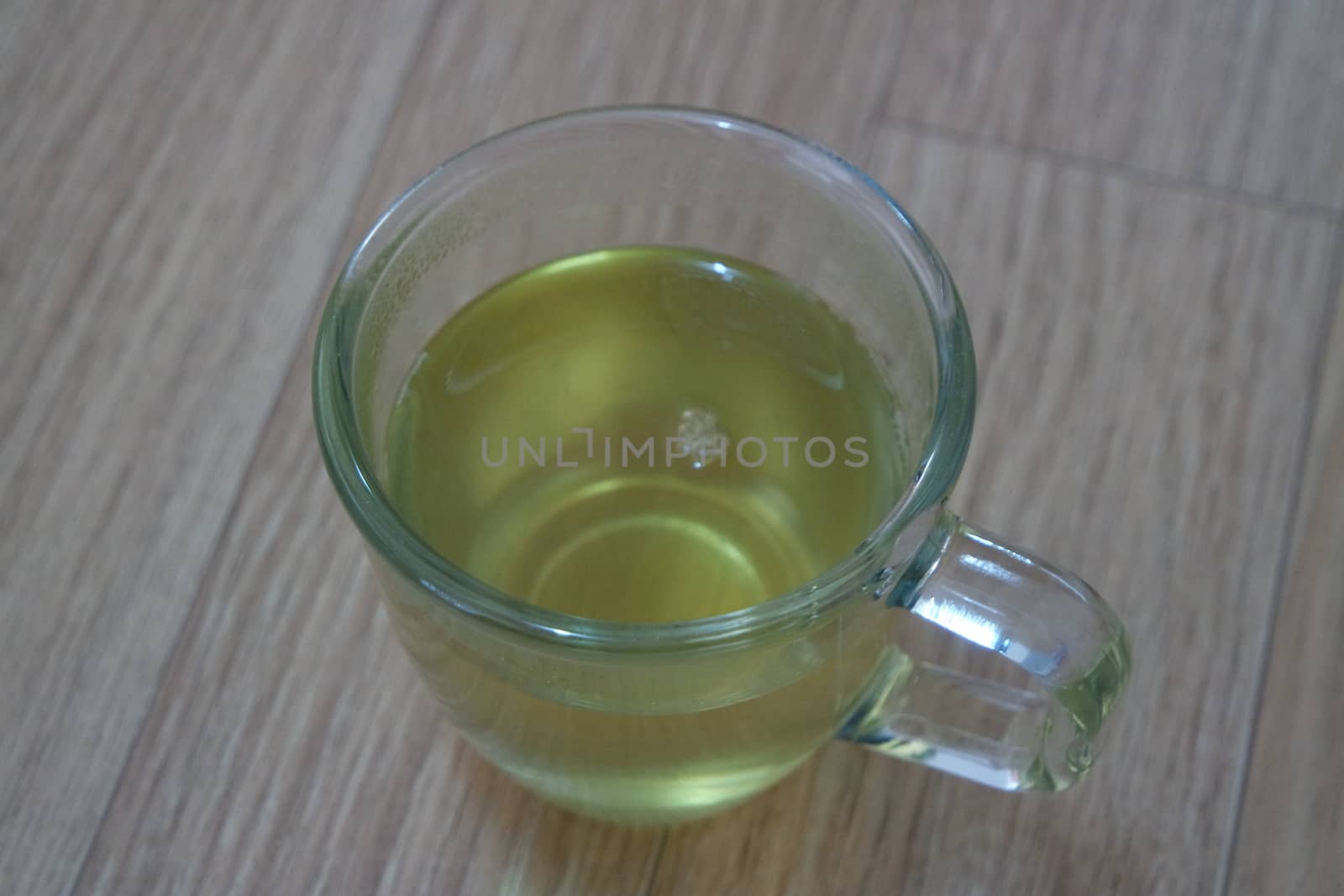 Glass cup having brewed fragrant green tea or qehwa or qahwa on the wooden floor. It is served with sugar or honey and nuts