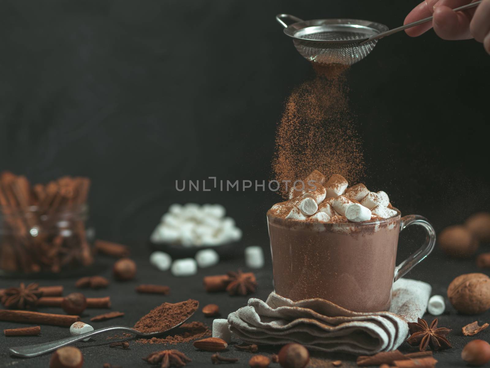 cinnamon powder flying over glass mug with hot chocolate by fascinadora