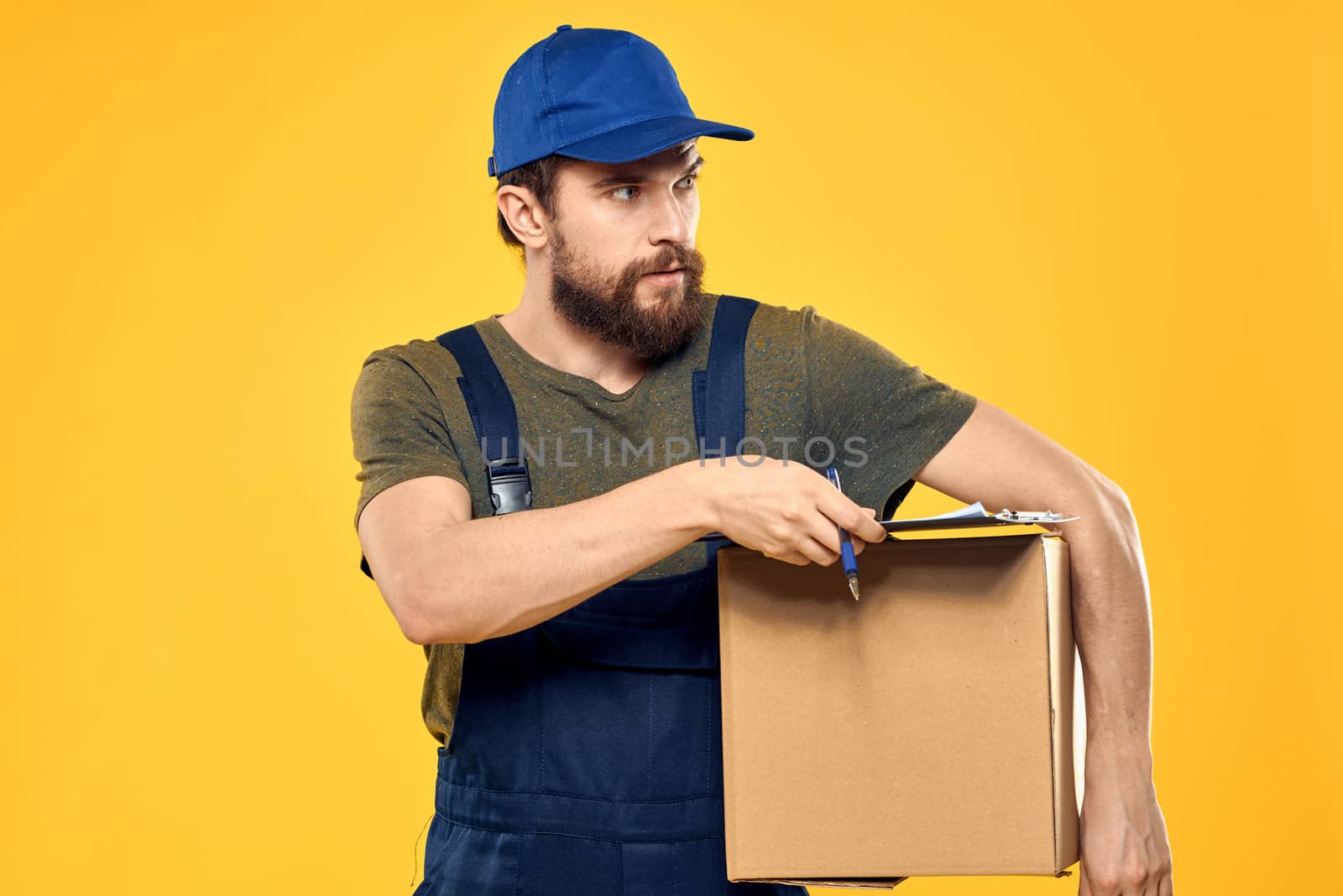 Worker male courier delivering boxes packaging documents yellow background by SHOTPRIME