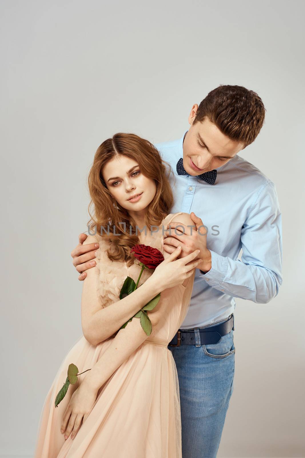 Young couple romance hug relationship dating red rose light studio background by SHOTPRIME