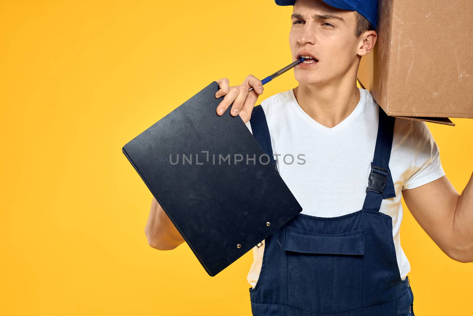 Working man in uniform with box hand delivery loading service yellow background. High quality photo