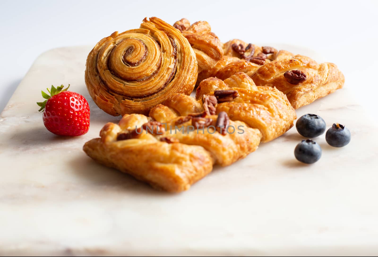 selection of French, Danish pastries with summer fruits on white marble background. Breakfast, morning treat, continental cafe