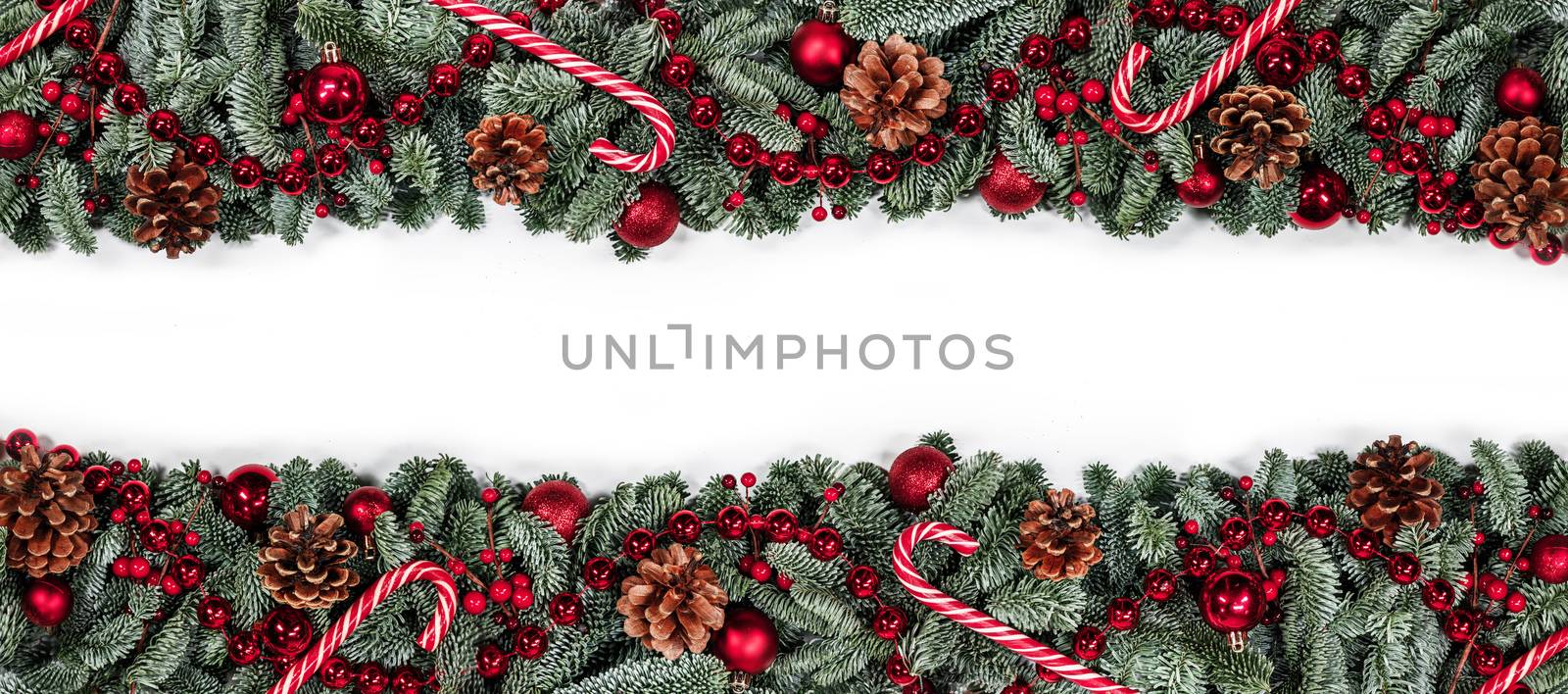 Christmas border frame design copmosition of noble fir tree branch and red decorations balls baubles berries pine cones isolated on white background