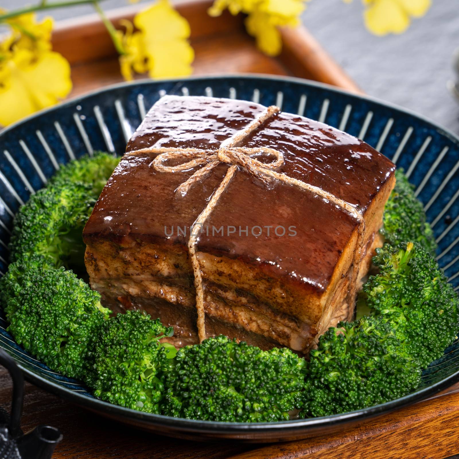 Dong Po Rou (Dongpo pork meat) in a beautiful plate with green vegetable, traditional festive food for Chinese new year cuisine meal, close up.