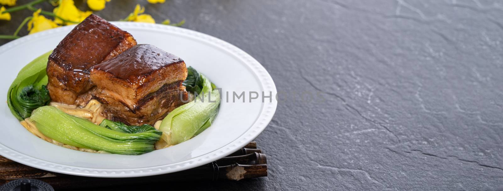 Dong Po Rou (Dongpo pork meat) in a beautiful plate with green vegetable, traditional festive food for Chinese new year cuisine meal, close up.