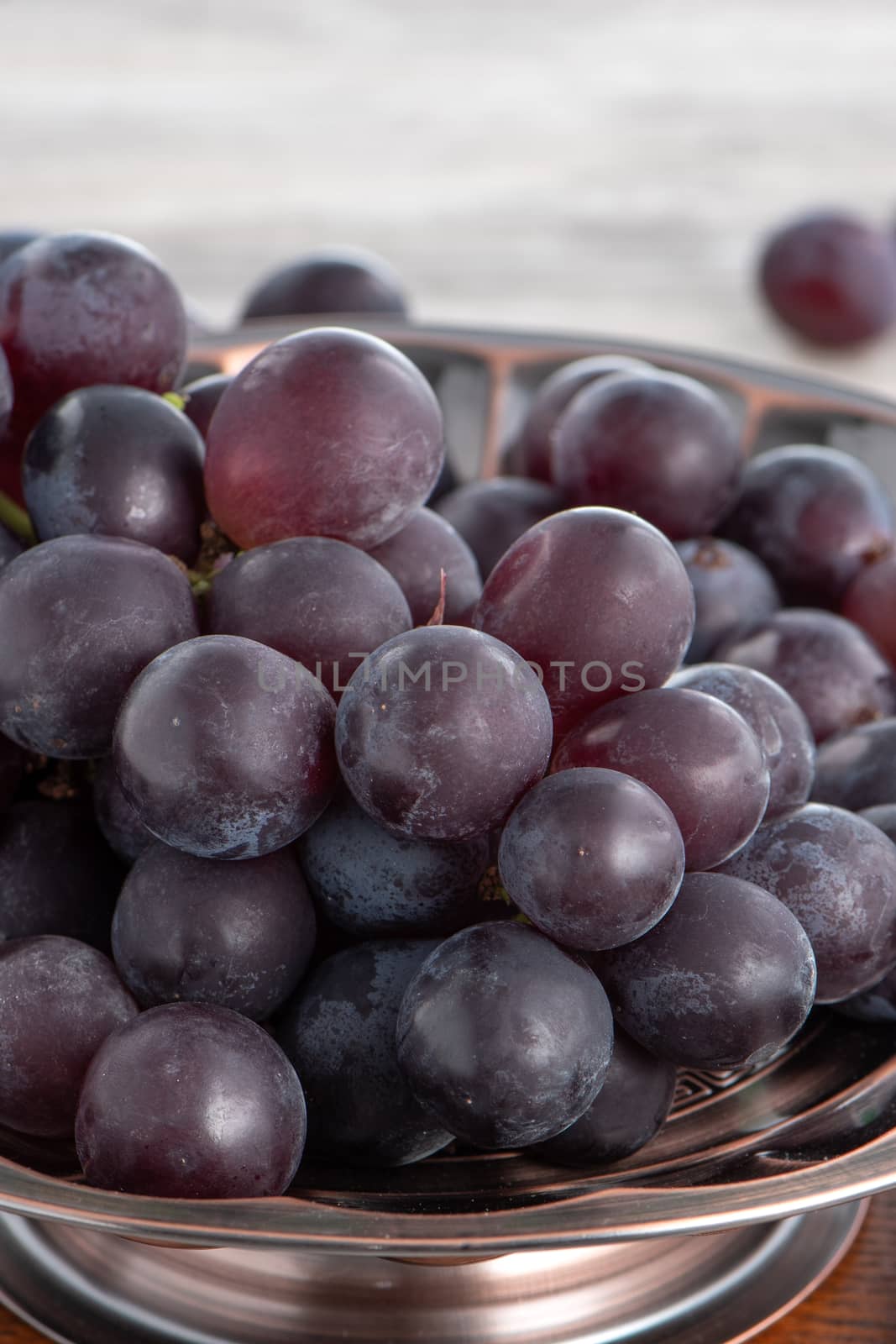 Delicious bunch of grapes fruit on a plate over wooden table background.
