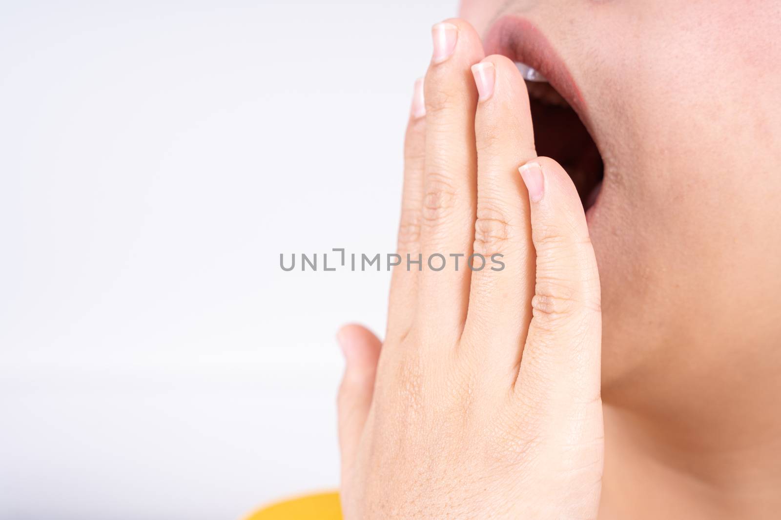 Asian woman are yawning covering open mouth with hand after she wake up. Healthcare medical or daily life concept. by mikesaran