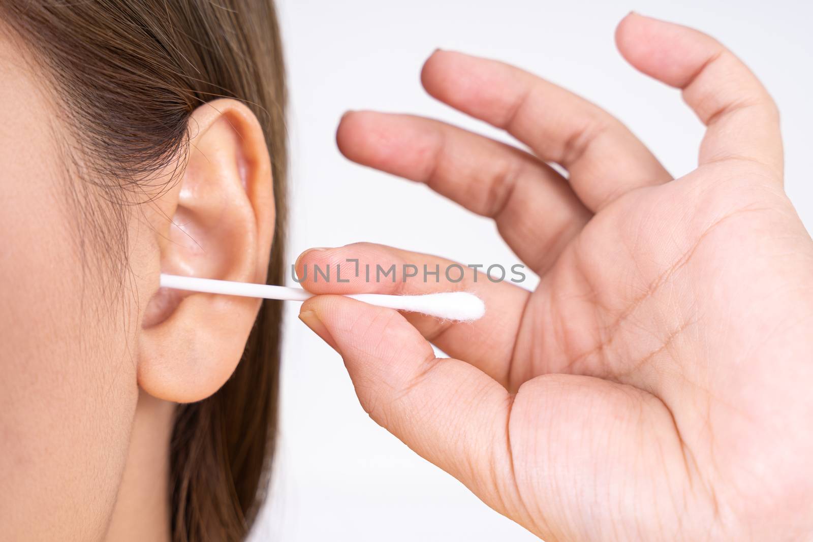 woman cleaning her ear with a cotton swab. A woman suffered an infection after using the sticks incorrectly.