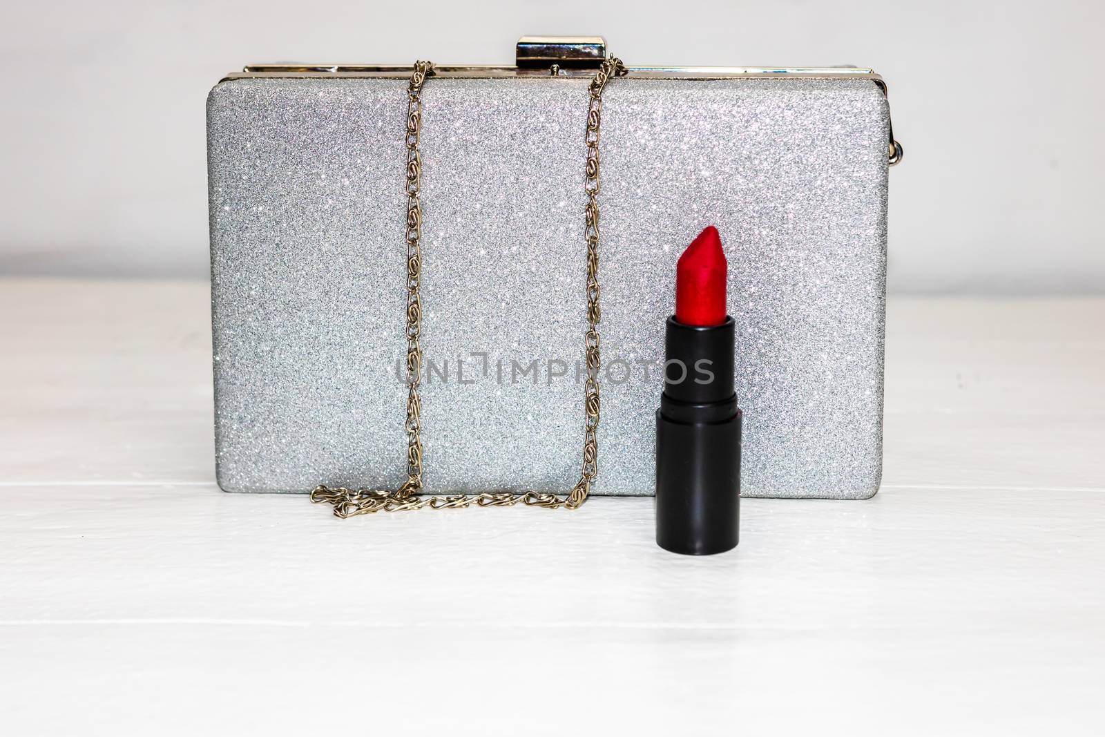Glittery silver clutch bag with red lipstick isolated on white b by vladispas