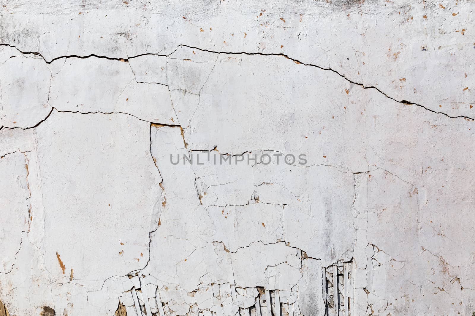 poor wattle and daub cracked stucco wall with white plaster.