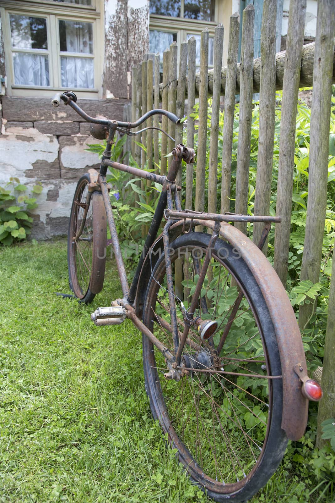 Old rusty bicycle leaning against a wooden fence