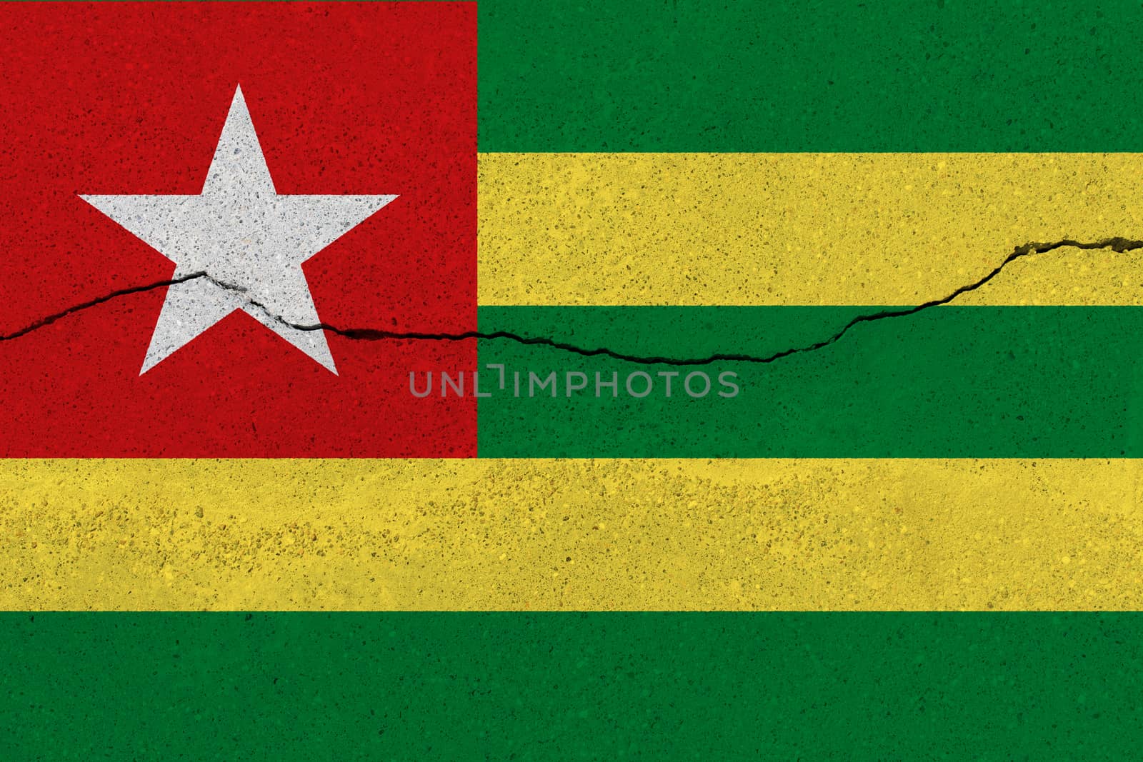 Togo flag on concrete wall with crack. Patriotic grunge background. National flag of Togo