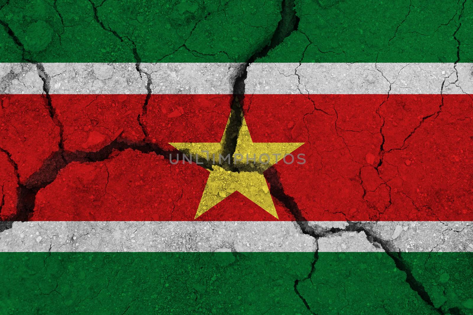 Suriname flag on the cracked earth. National flag of Suriname. Earthquake or drought concept