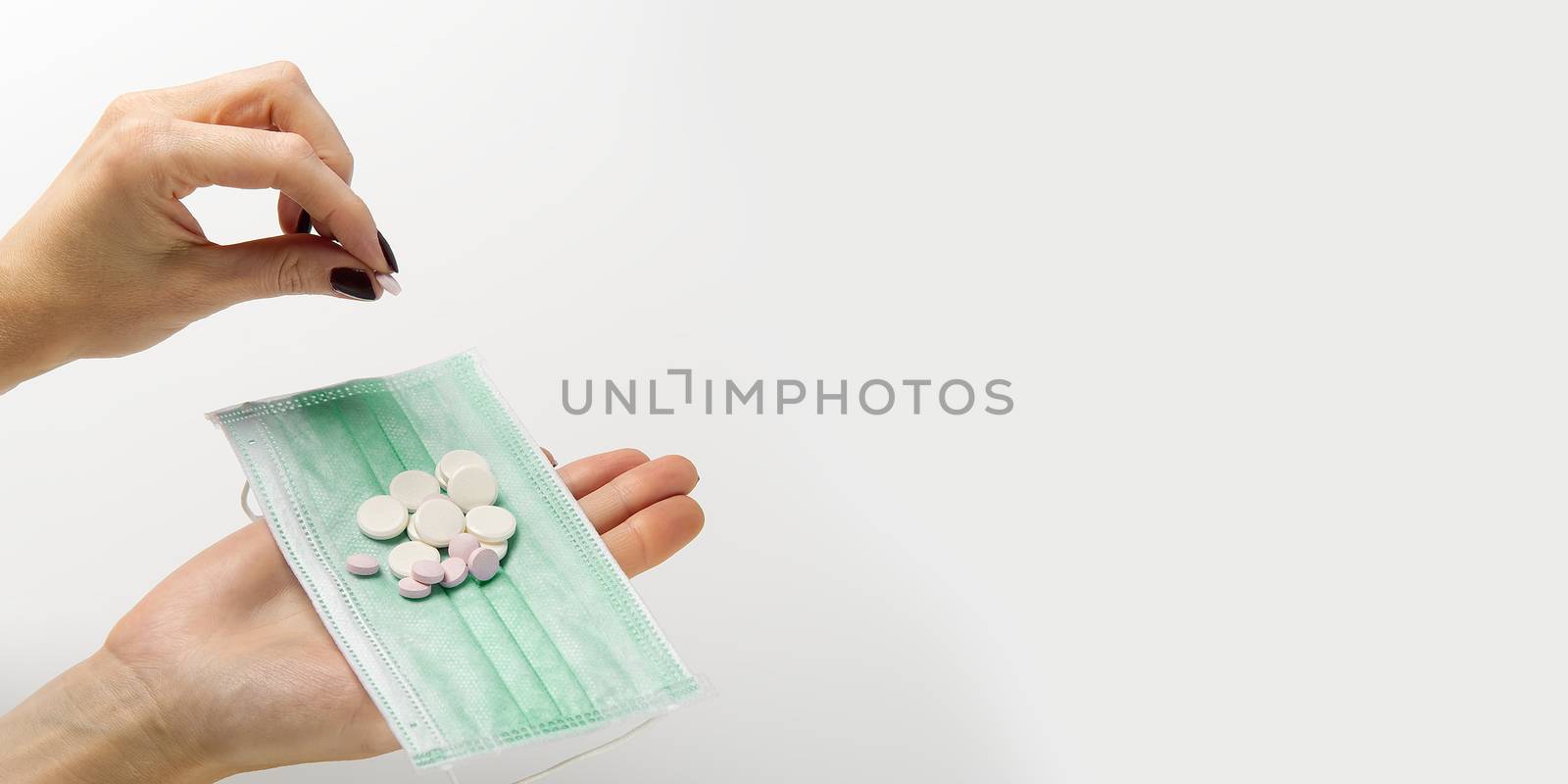 concept covid vaccine pills. COVID-19. Medical mask on a hand with white background. Medicine pills or Vaccine against the virus. Hand holds medical face mask and white pills.