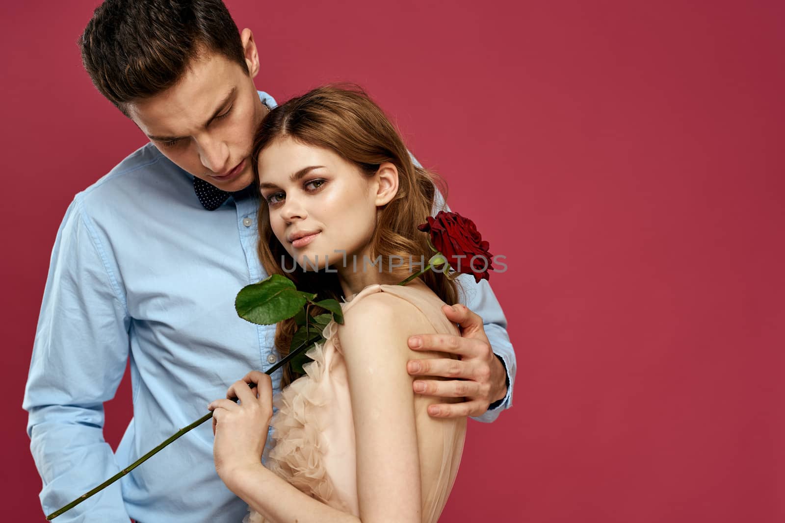 Lovers people with rose in hands on pink isolated background hug emotions happiness romance feelings by SHOTPRIME