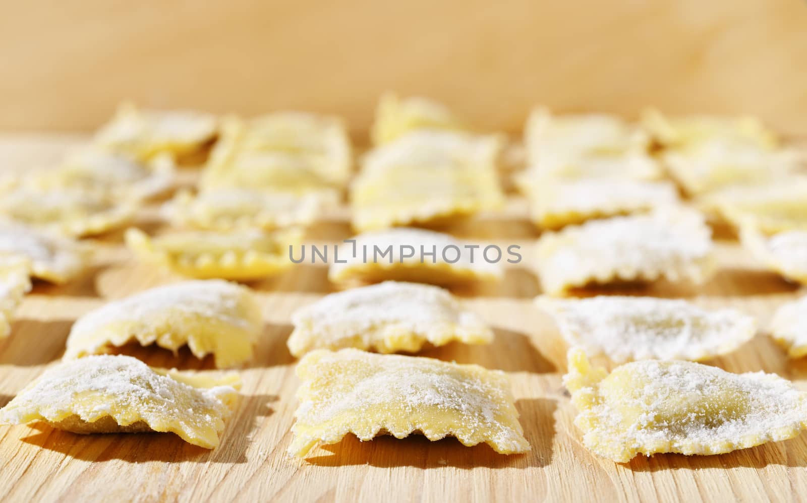 Square ravioli on wooden table , white flour all around ,ravioli on several lines