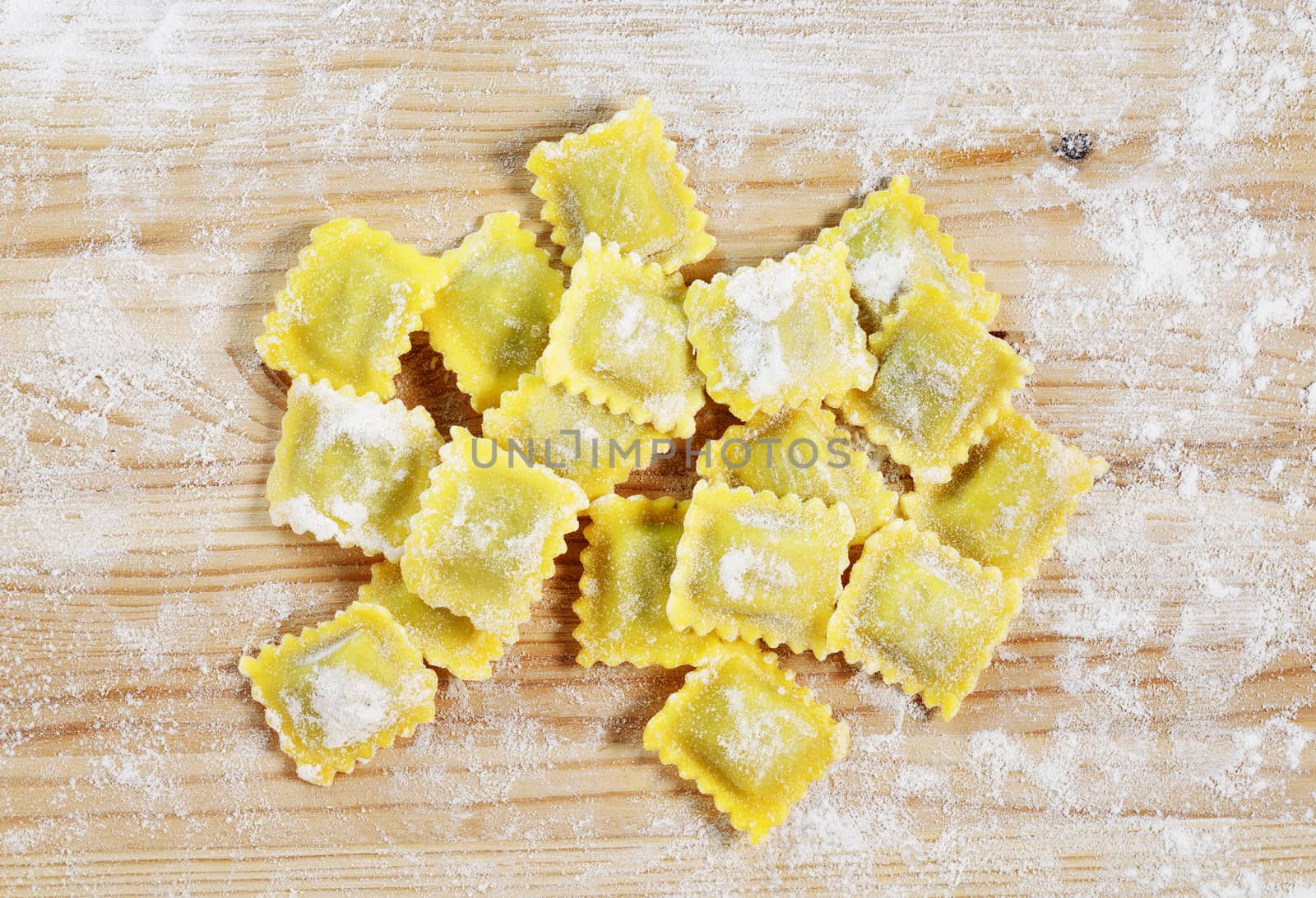 Square uncooked ravioli on wooden table ,white flour all around