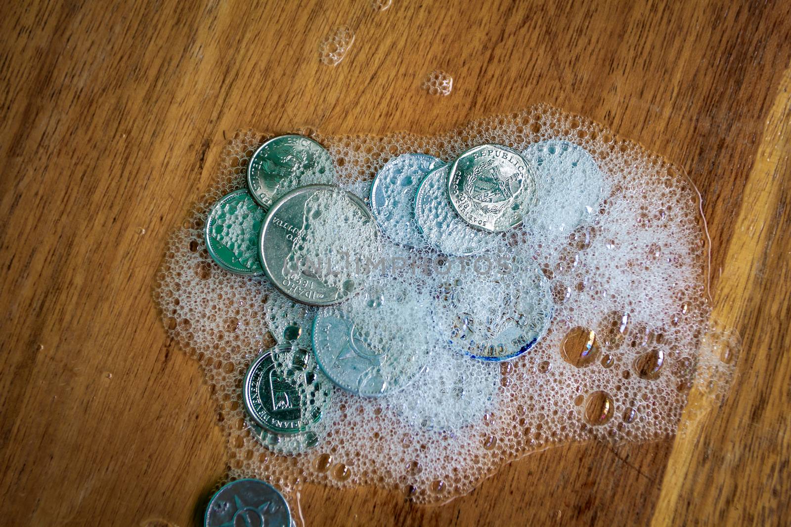 Group of coins covered in foam on a wooden surface