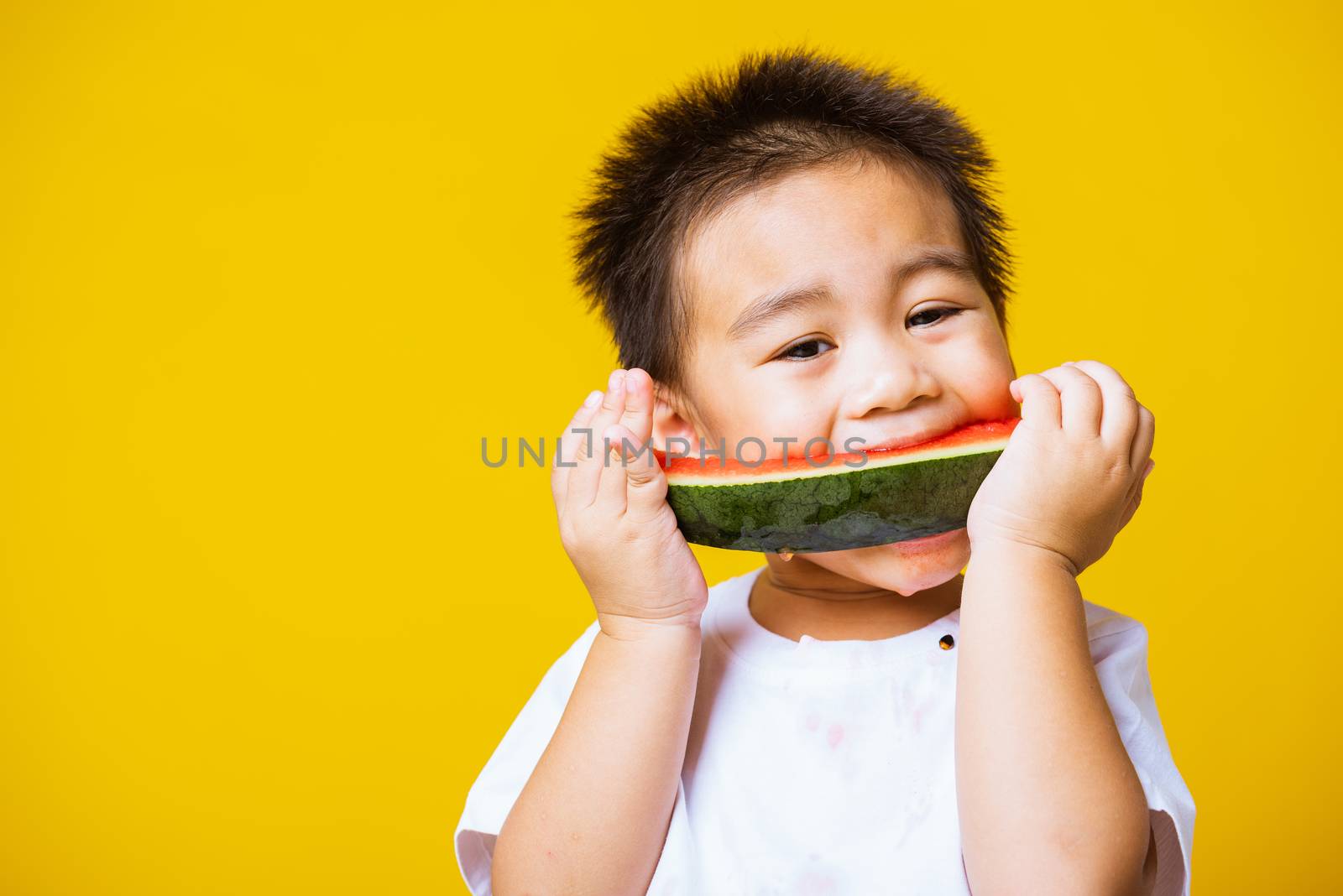 Happy portrait Asian child or kid cute little boy attractive laugh smile playing holds cut watermelon fresh for eating, studio shot isolated on yellow background, healthy food and summer concept