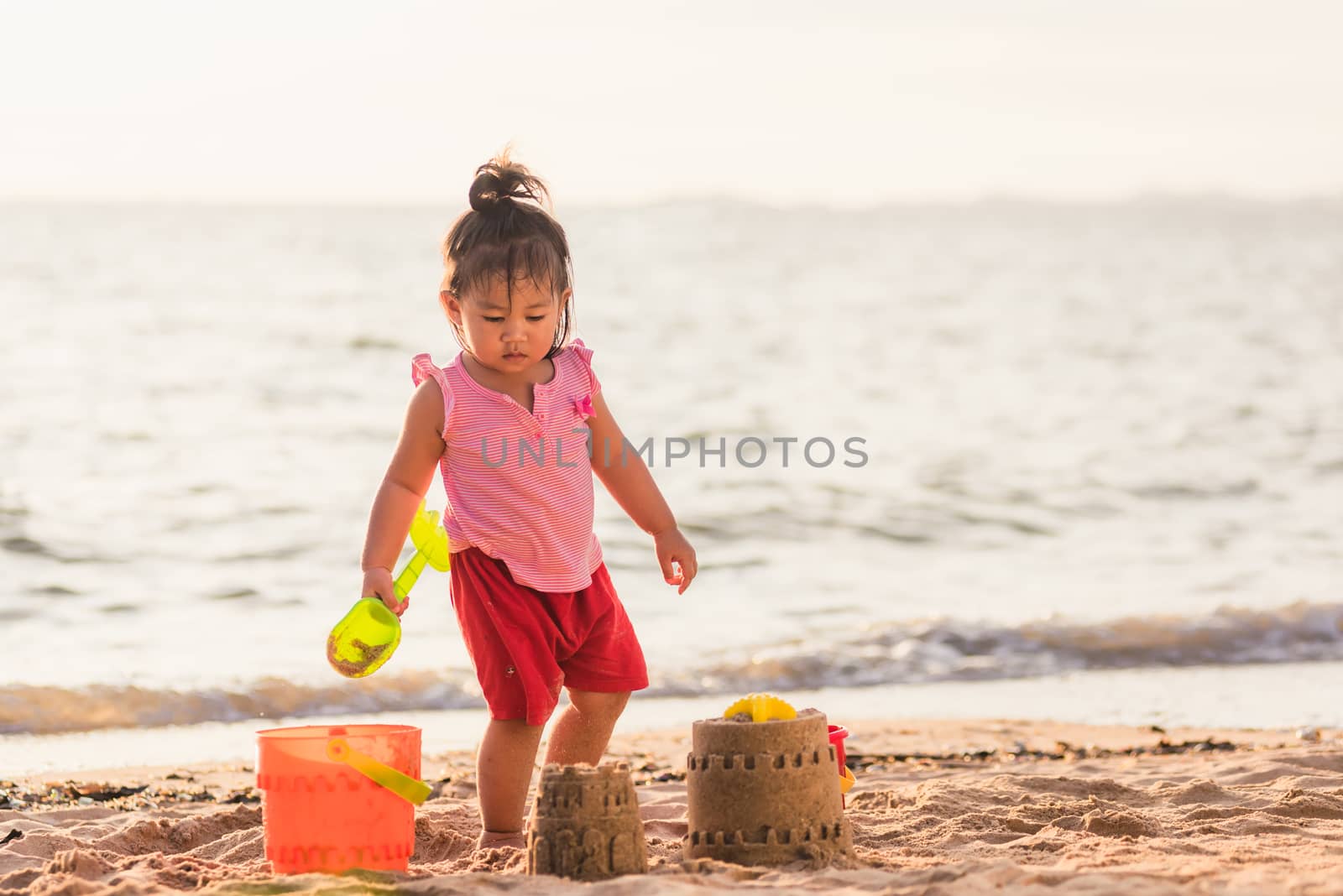little girl playing sand with toy sand tools by Sorapop