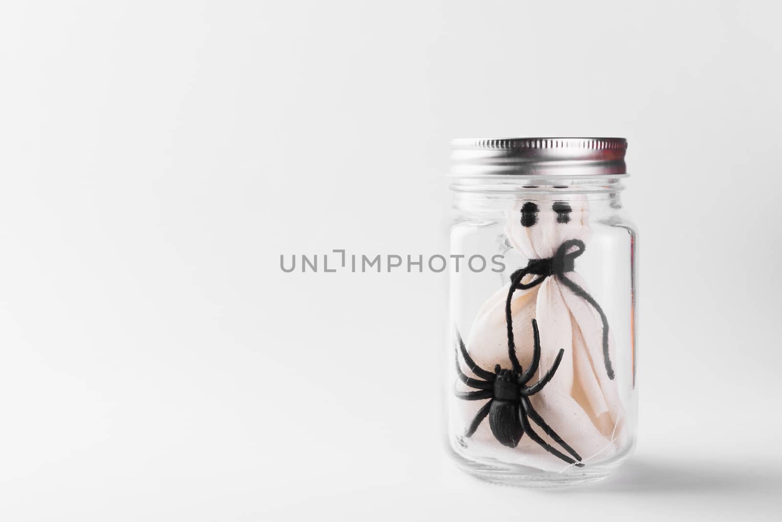 Funny Halloween day decoration party, The white ghost scary face and black spider in jar glass, studio shot isolated on white background, Happy holiday concept
