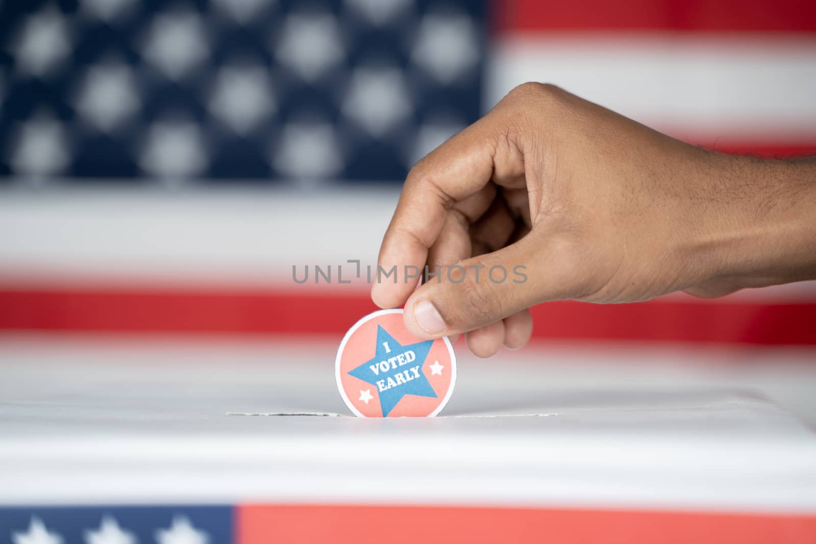 Close up of Hands placing I voted Early sticker inside the ballot box - Concept of Early voting in us election. by lakshmiprasad.maski@gmai.com