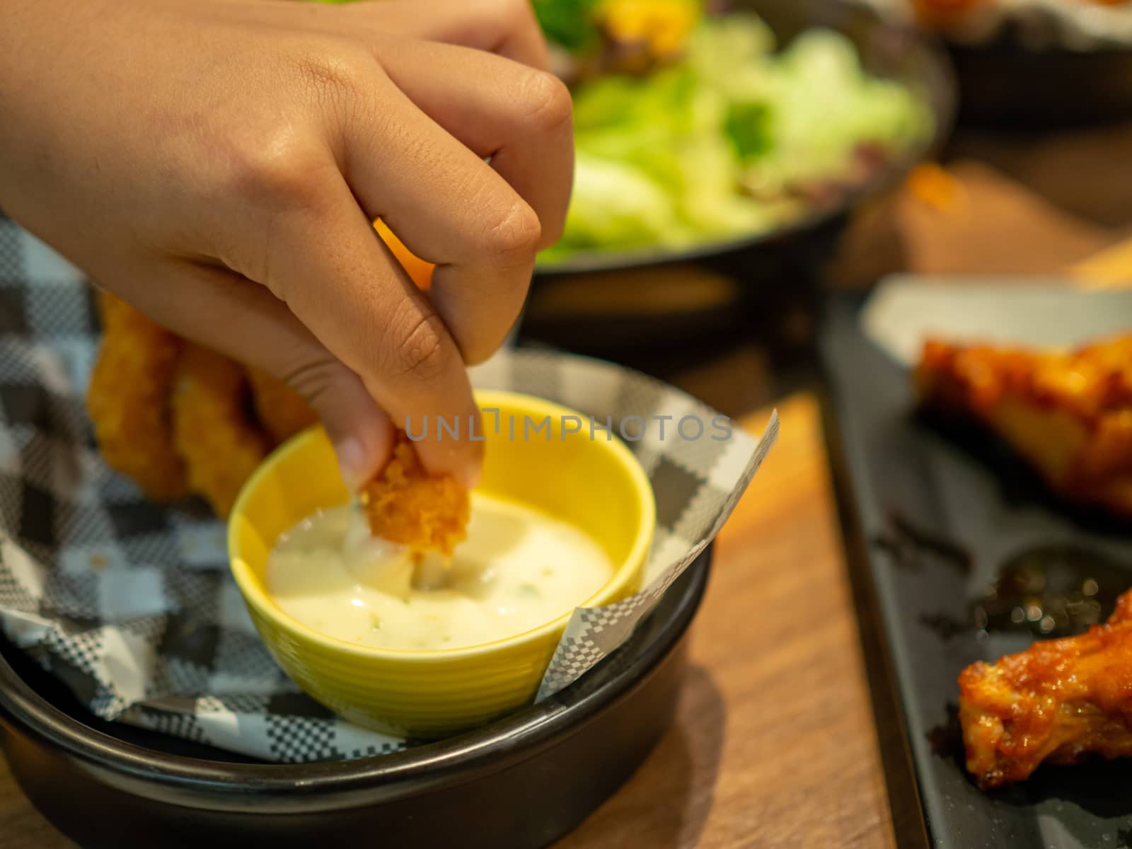 Human hand holding fish finger and dipping on mayonnaise sauce w by Unimages2527