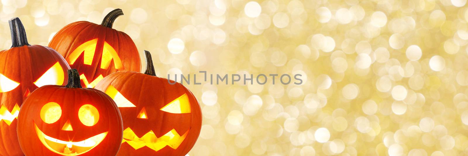 A collection of Jack O Lantern Halloween pumpkins with various different design on golden bokeh background with copy space