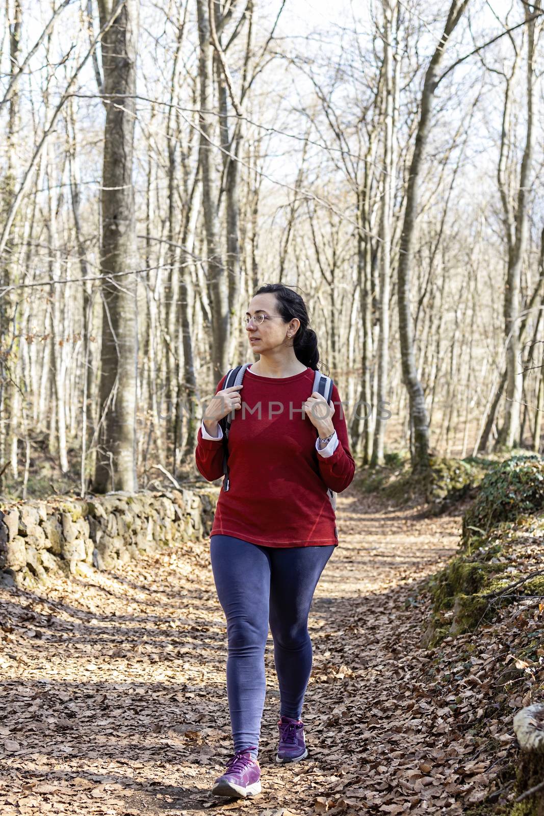Sporty Spanish woman walking on the pathway in the forest by Digoarpi