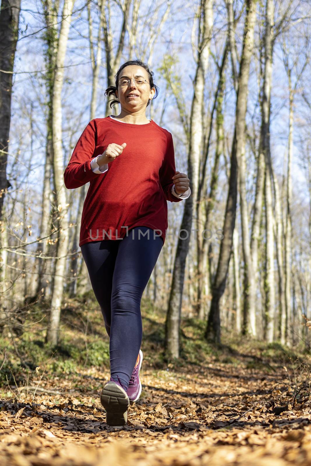 Pretty spanish woman running in the forest in a sunny day in springtime by Digoarpi