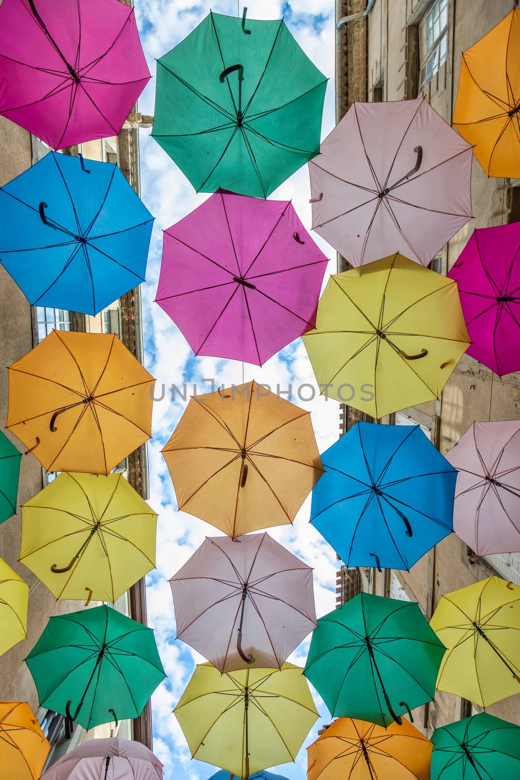 Colorful umbrellas cover a shopping street in Carcassonne, Aude, Occitanie, France by Digoarpi