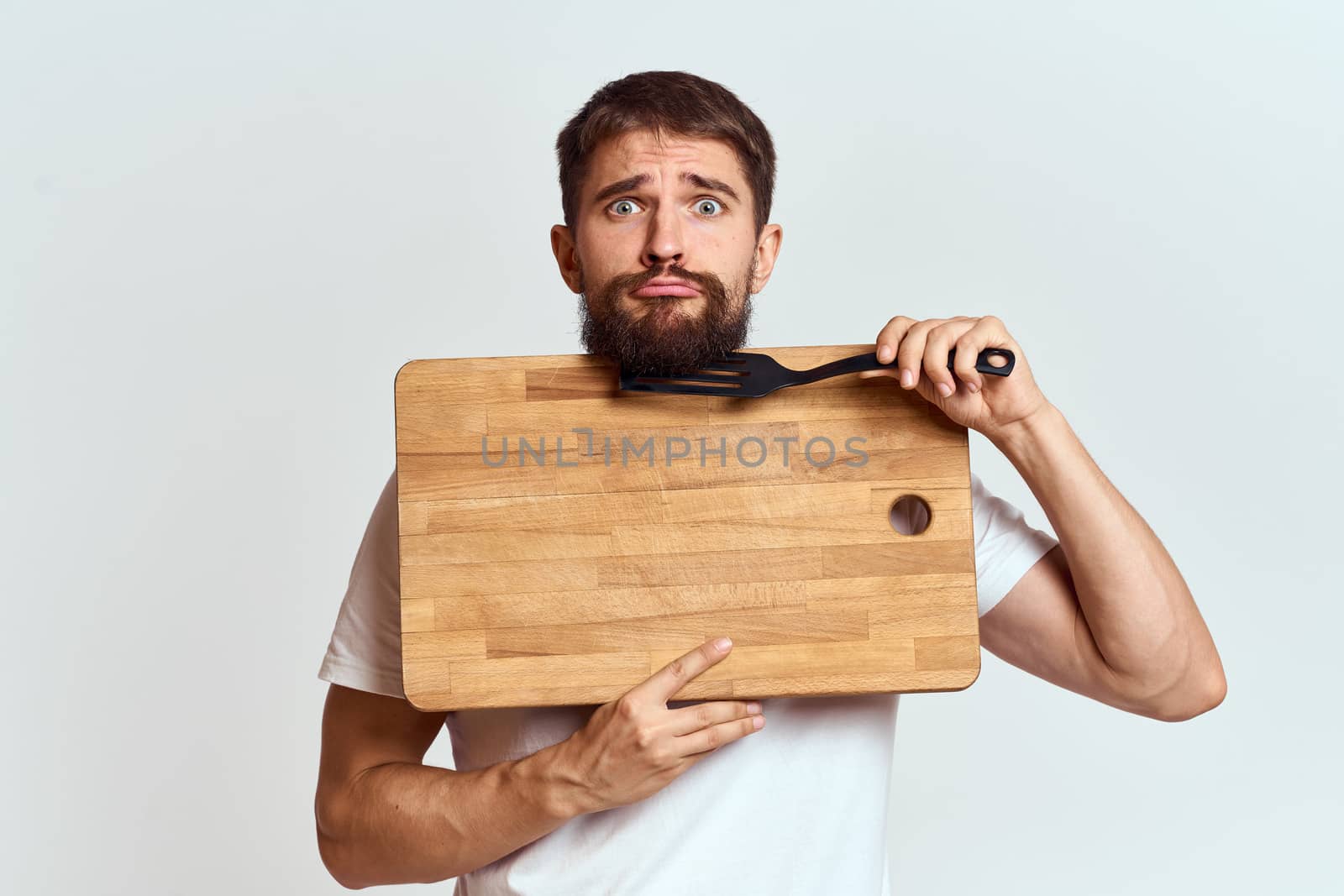Man with a kitchen wooden board and with a shovel on a light background emotions white t-shirt model by SHOTPRIME