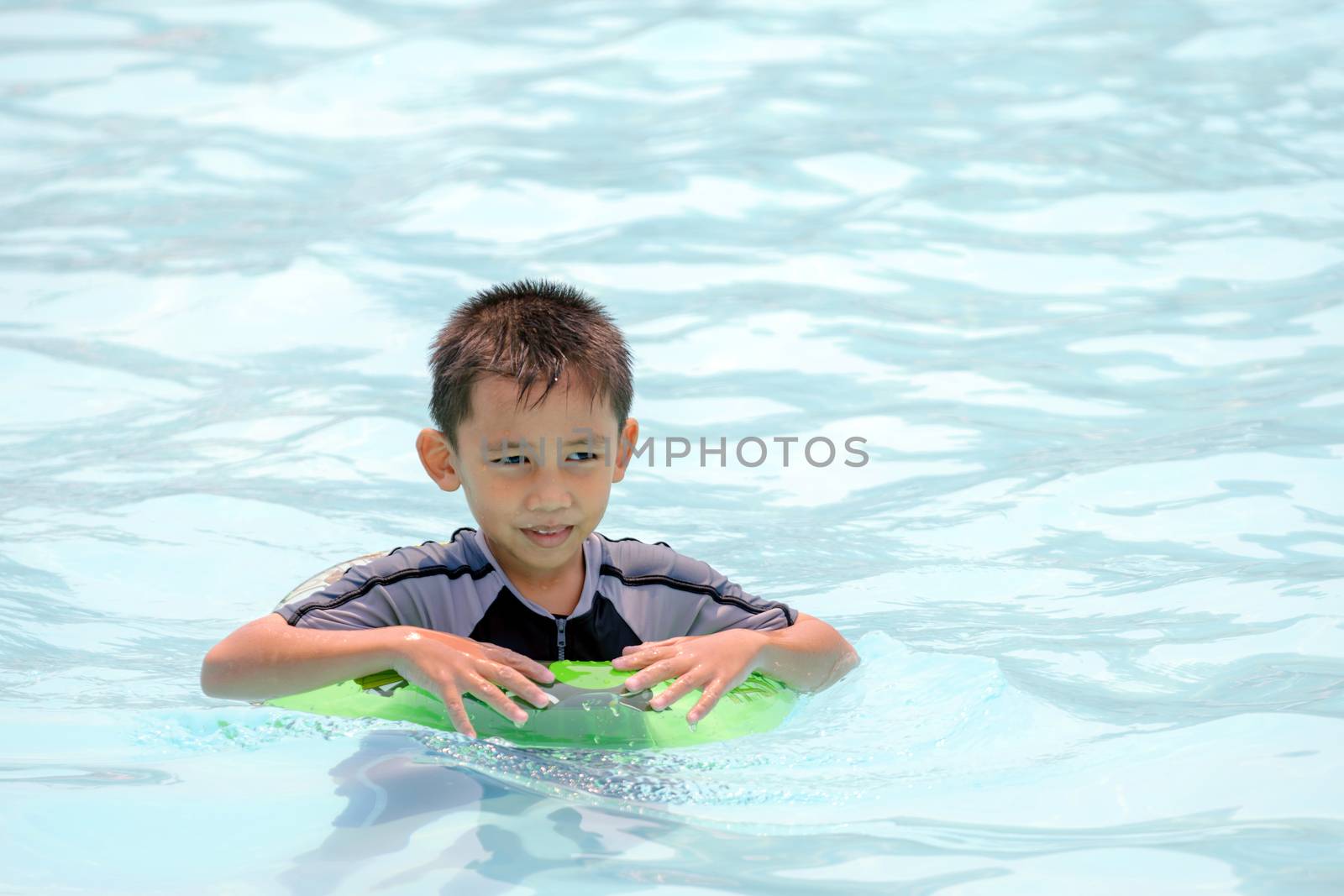 Asian boy in swimwear, swimming fun in the pool.