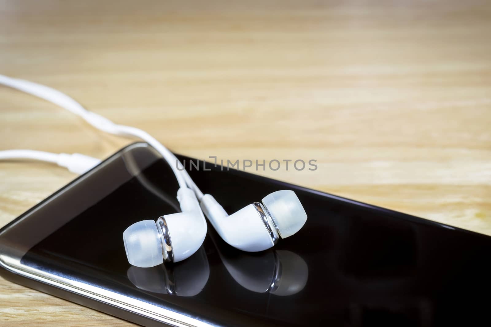 Headphone or earphone and smart phone on wooden background.