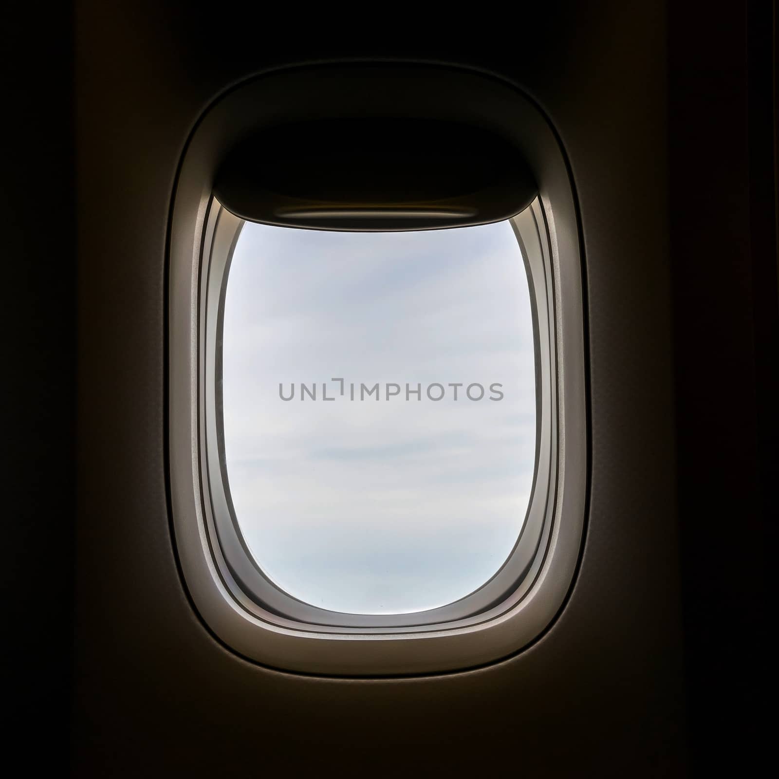 Closeup of the airplane window with the clouds sky background.