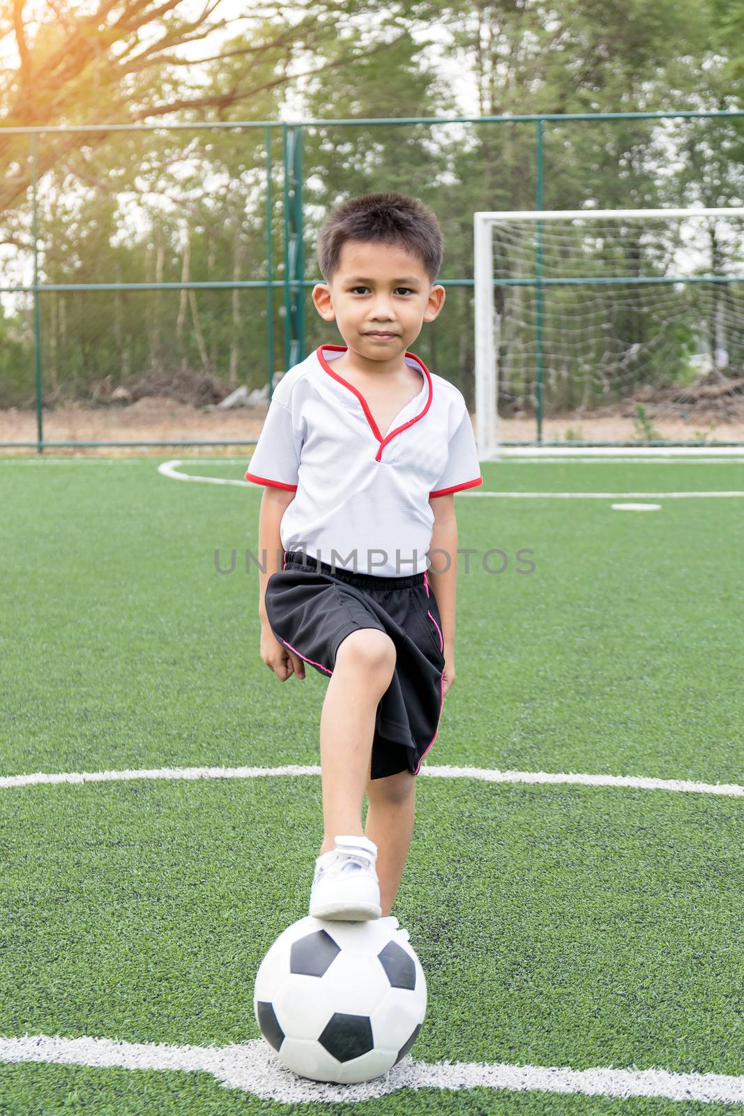 The boy was playing soccer on the football field with happiness.