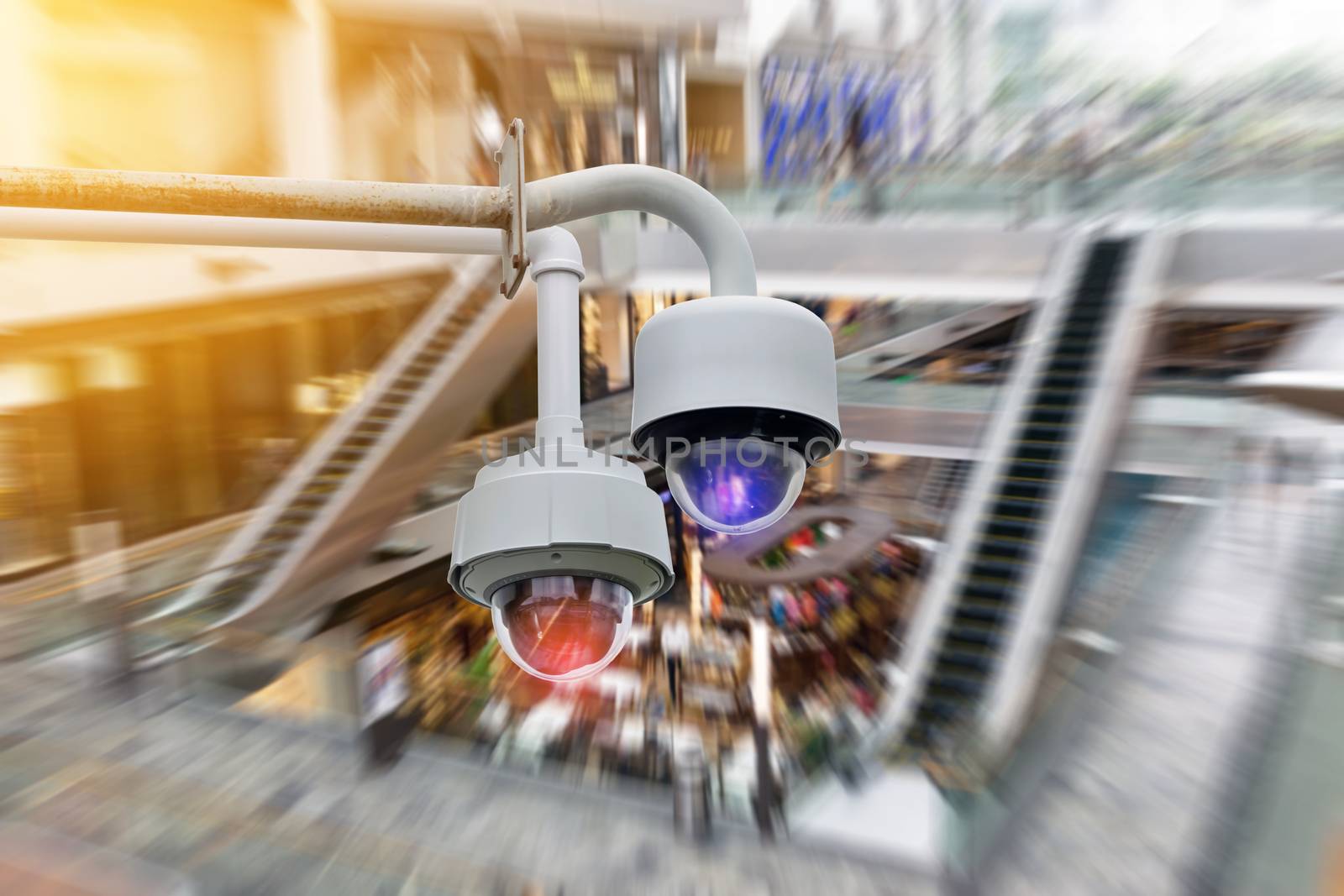 Closeup CCTV security camera on blurred inside shopping mall background.