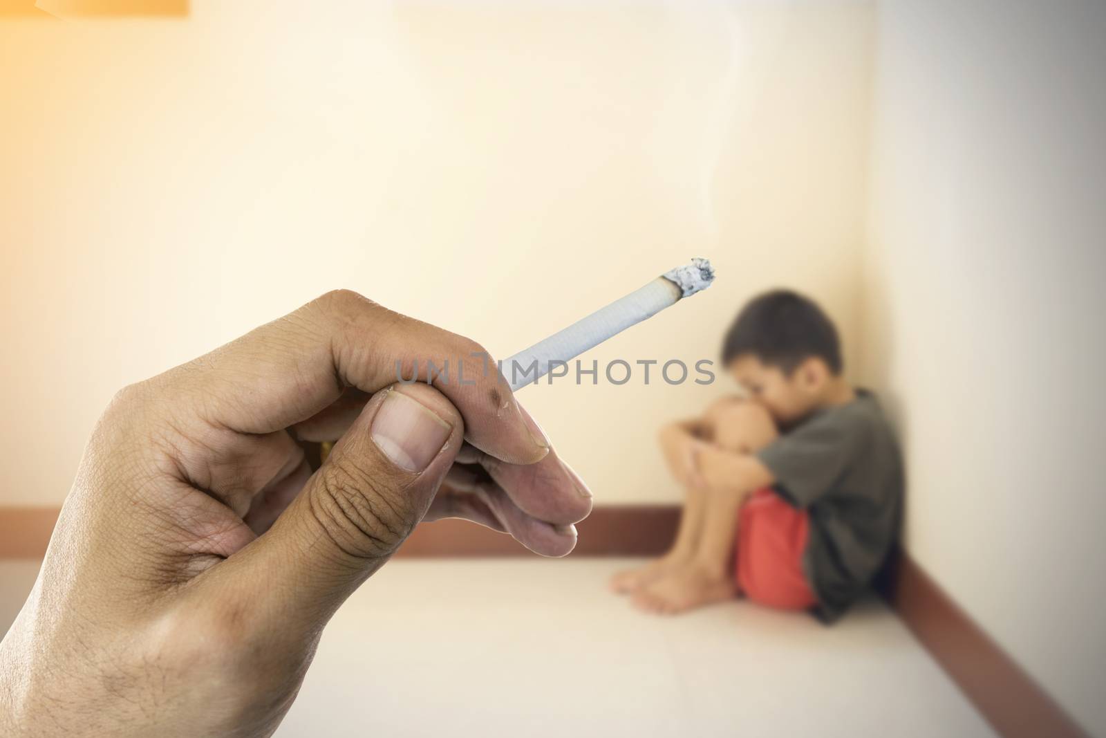 Closeup a cigarette in hand with blurred of the boy hugged her knees in tears in a corner of the room.