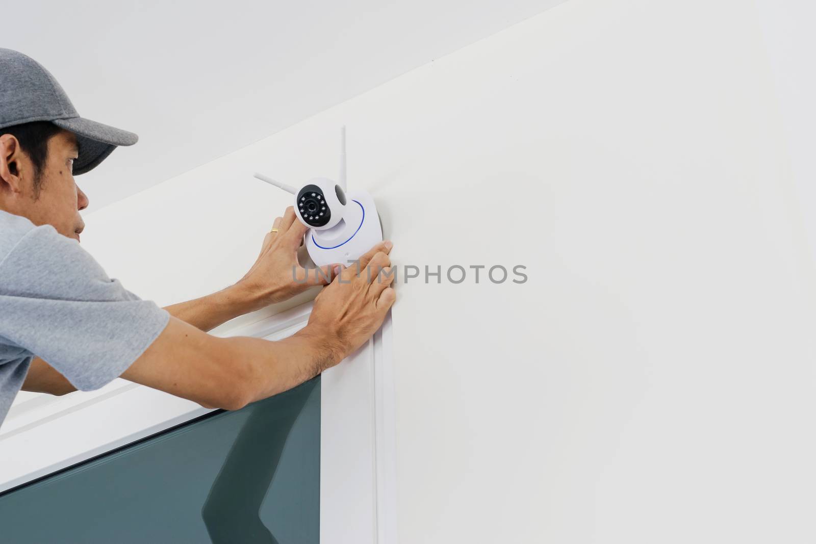 Technicians are installing a wireless cctv camera on the wall, can connect to the Internet, and control the camera via a smartphone or tablet.